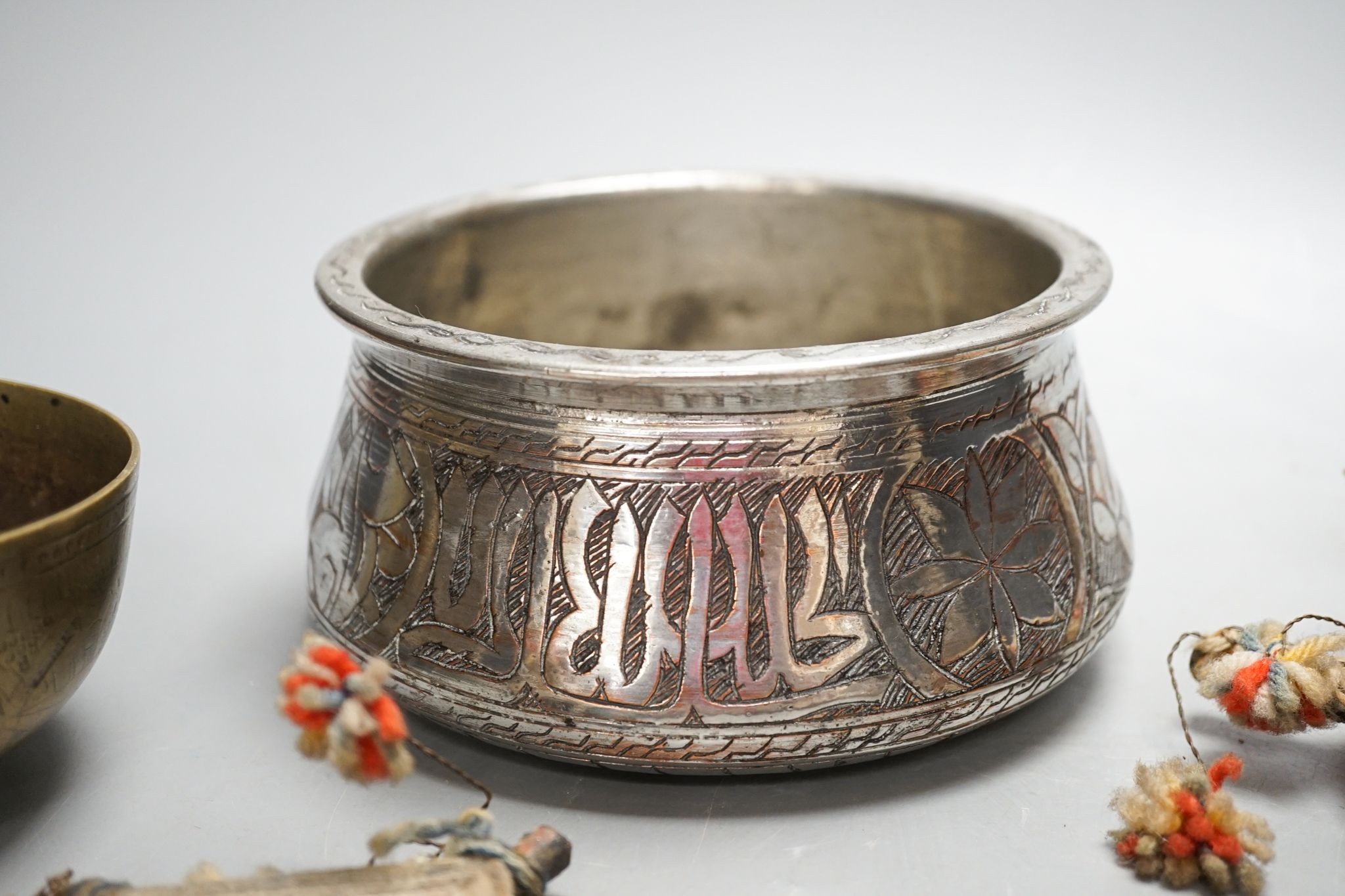 A Himalayan brass bell and bowl, a woolwork finial, 43 cm high, an Islamic tinned metal censer (4)